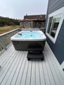 Soak away your cares in the brand new private hot tub, perched on a spacious deck overlooking coastal greenery and neighboring homes—perfect for unwinding after a day exploring the coast.