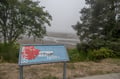 Historic marker overlooking a misty bay provides context about the area's rich past and scenic natural surroundings.