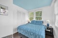 Your bright bedroom features a lovely sky-blue ceiling and soft botanical bedding, creating a peaceful retreat with garden views.