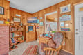 Cozy up in this charming wood-paneled living room with comfy seating, books, and beach-themed decor for your perfect coastal getaway.