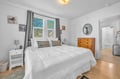 Sink into crisp white linens in your peaceful bedroom, where natural light streams through windows and warm wood floors create a cozy retreat.