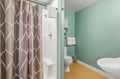 Refresh in your private bathroom with a full tub and shower, modern fixtures, and cheerful turquoise walls that set a welcoming, coastal-inspired tone.