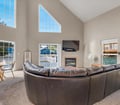 Sink into the curved leather sectional and enjoy the soaring vaulted ceilings that fill this bright, airy living space with natural light and warmth from the cozy fireplace.