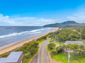 Aerial view capturing the stunning coastal location, with pristine beach stretches and rolling hills defining the scenic neighborhood surrounding the property.