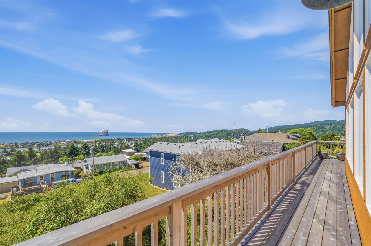 Elevated deck offers sweeping coastal and mountain vistas, placing guests in a scenic Oregon beach community setting with ocean rock formations visible in the distance.