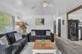 Unwind in this thoughtfully designed living space featuring plush seating, natural light streaming through large windows, and a ceiling fan to keep you comfortable. Modern touches blend seamlessly with cozy furnishings for your perfect retreat.
