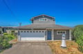 Charming coastal-style home features nautical details and convenient garage parking under brilliant blue skies.