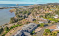 Aerial view of coastal community with ocean, river, and forested hills creating a scenic Pacific Northwest setting.