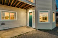 Modern gray exterior featuring a welcoming green front door and covered entry porch with exposed beam details.
