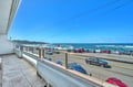 Ocean view balcony overlooks coastal highway and sandy beach with rolling waves under brilliant blue skies.