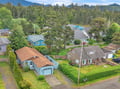 Aerial view of a residential neighborhood nestled among lush evergreen forests and mountain foothills, showcasing the peaceful natural surroundings of the property.
