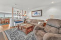 Unwind in your spacious living room with plush seating and coastal decor, where warm wood accents create the perfect atmosphere for relaxation.