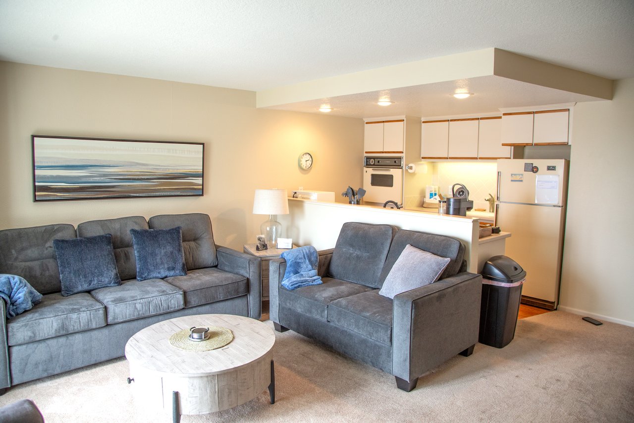 Sink into plush sofas in your open living space, where coastal artwork and a full kitchen invite you to unwind and feel completely at home.