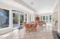 Bright sunroom with comfortable seating where you can enjoy morning coffee surrounded by garden views through floor-to-ceiling windows.