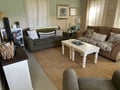 Relax in your cozy living space with plush sofas, coastal decor, and natural light streaming through plantation shutters for the perfect home-away-from-home feeling.