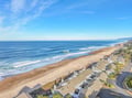 Stunning aerial view showcases pristine beachfront location with expansive sandy shores and rolling Pacific waves.