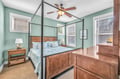 Drift off in your elegant four-poster bed surrounded by calming mint walls and warm wood tones, with gentle breezes from the ceiling fan.