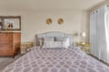 Unwind in your elegantly appointed bedroom featuring a plush upholstered headboard, premium linens, and thoughtful coastal touches that create the perfect retreat.
