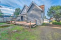 Charming coastal cottage with spacious deck and private parking, surrounded by mature trees in a peaceful neighborhood setting.