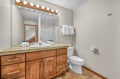 Freshen up in your private bathroom featuring warm wood cabinetry, granite countertops, and Hollywood-style vanity lighting for perfect morning routines.