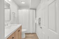 Step into a bright, spotless bathroom with warm wood accents and crisp white linens ready for your arrival.