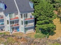 An aerial view showcasing the property's multi-level design with spacious private balconies overlooking lush natural greenery and coastal landscape.