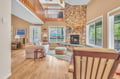 Relax in your spacious living room featuring soaring ceilings, stunning stone fireplace, and warm wood floors that create the perfect cozy retreat.