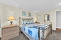 Sleep peacefully in your coastal-themed bedroom featuring a brass bed frame, nautical art, and soft bedside lighting for ultimate relaxation.