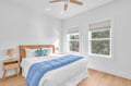 Drift off in this bright, airy bedroom where natural light streams through large windows and a gentle ceiling fan keeps you cool.