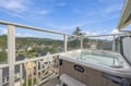 Soak in your private hot tub while overlooking peaceful neighborhood rooftops and green hills stretching to the horizon under an open sky.