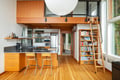 Step into your sleek loft where warm wood tones meet modern design, complete with a fully equipped kitchen and cozy library nook.