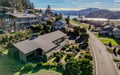 Aerial view of coastal property nestled in residential neighborhood with stunning lakefront and mountain backdrop.