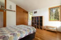 Your serene bedroom offers warm wood floors and forest views through large windows for peaceful mornings.