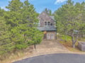 Charming cedar-shingled cottage nestled among towering pines with private driveway and garage for convenient arrival.