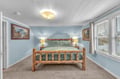 Drift off in your cozy log bed surrounded by soft blue walls and scenic artwork that creates a peaceful mountain retreat atmosphere.