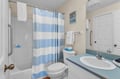 Your private bathroom features a tub-shower combo with cheerful blue striped curtains and fresh towels waiting for you.