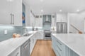 Your modern kitchen features gleaming quartz counters, stainless appliances, and soothing blue-green backsplash—perfect for cooking memorable meals together.