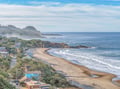 A stunning coastal area featuring sandy beaches, rolling waves, and charming hillside homes overlooking the Pacific Ocean.