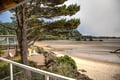 Coastal property located along a sandy beach cove, surrounded by evergreen forest and rocky outcrops, offering direct waterfront access and outdoor seating areas.