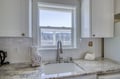 The bright kitchen features granite counters, modern fixtures, and a window framing scenic water and forest views—a perfect backdrop for your morning coffee ritual.