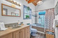 Your private bathroom features charming beamed ceilings, tiled shower-tub combo, and thoughtful touches for a comfortable stay.