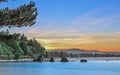 A stunning coastal vista frames the property's natural surroundings at sunset, with tranquil waters and forested hillsides creating a peaceful retreat setting.
