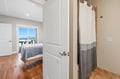You'll find crisp white doors and warm wood floors framing your space, while the nearby bedroom invites you to rest with stunning ocean views just beyond the window.