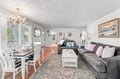 Relax in your open-plan living and dining space, where plush seating, warm hardwood floors, and coastal artwork create a cozy atmosphere for unwinding after your day's adventures.