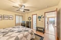 Your coastal-themed bedroom with ocean art, a ceiling fan, and a glimpse of the sea beyond. Soft tones and sea turtle decor create a relaxing beachside retreat.