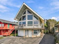 This distinctive A-frame vacation home features dramatic windows and a spacious balcony, located in a quiet residential neighborhood. The property includes parking and seasonal outdoor space for your stay.