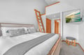 Drift off in your cozy bedroom featuring crisp linens and charming coastal artwork, with convenient loft access above.