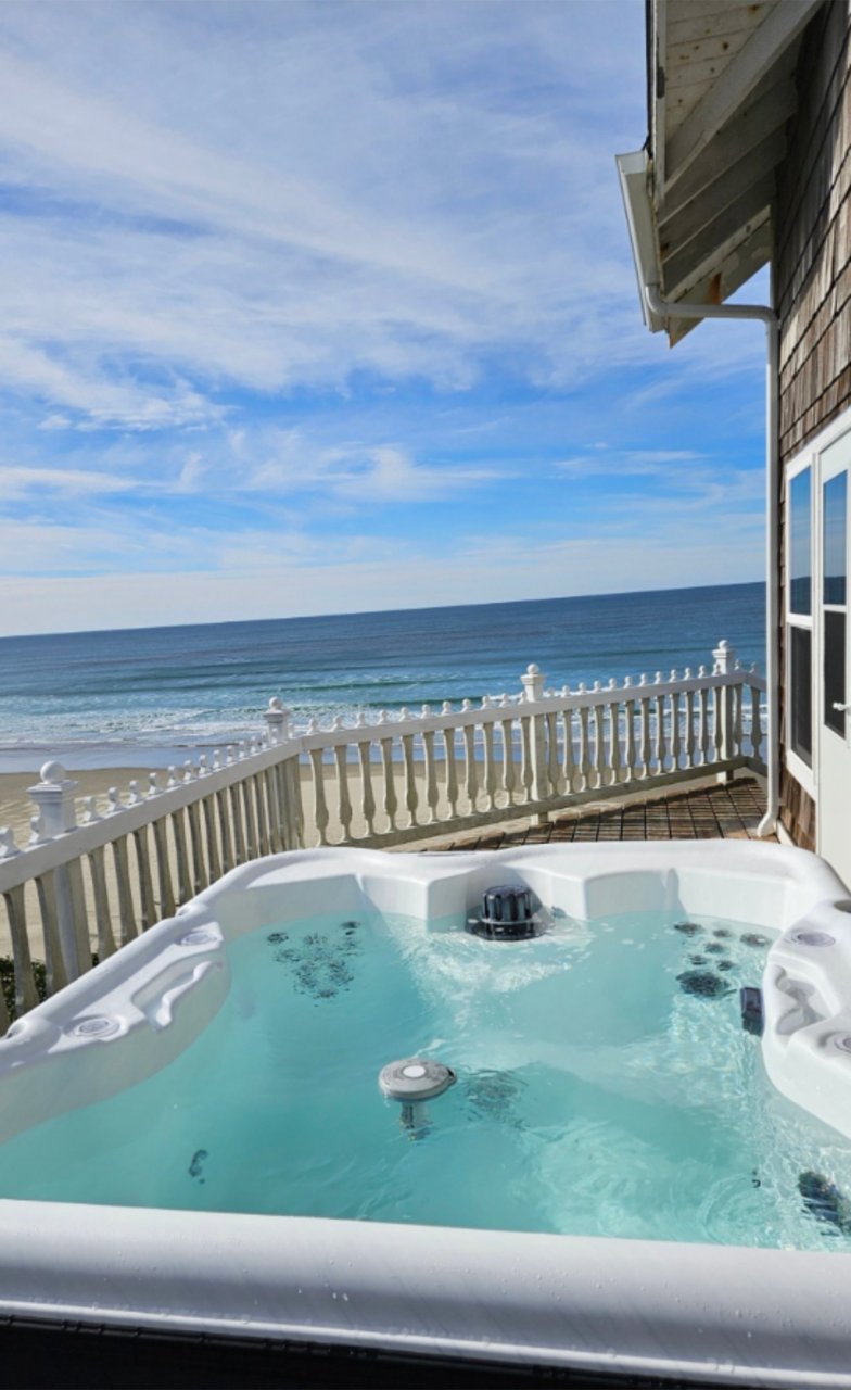 Soak in the bubbling hot tub on your private deck while ocean waves roll in just steps away—your perfect beachfront retreat.