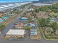 Aerial view of a coastal town featuring the property nestled between forested hills and Pacific Ocean beaches.