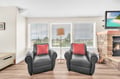 Unwind in your cozy living space with twin leather chairs by the fireplace, perfect for morning coffee or evening relaxation.